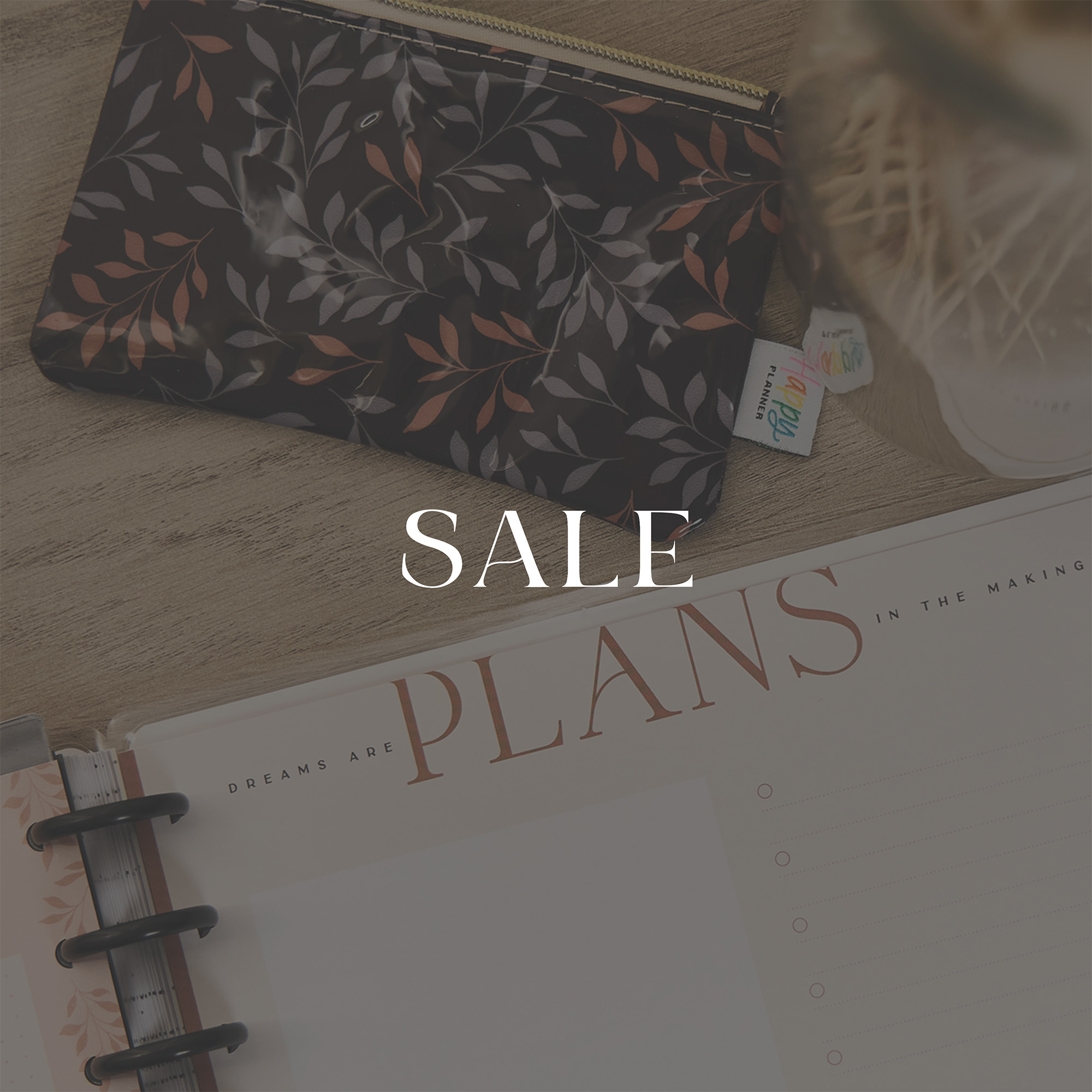 ```html
<img src=_image.html alt="Desk with floral pouch and planner, overlaid text 'SALE'." />
```